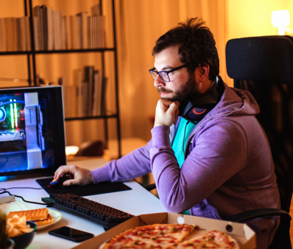 Man using computer with a pizza at his side